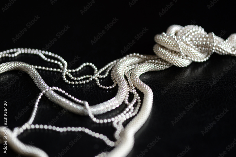 Metal necklace tied in a knot on a dark background close up