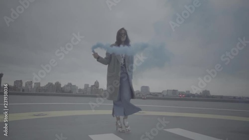 Cute woman with smoke bomb over city background. Slow motion, s-log, ungraded photo