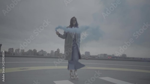 Cute woman with smoke bomb over city background. Slow motion, s-log, ungraded