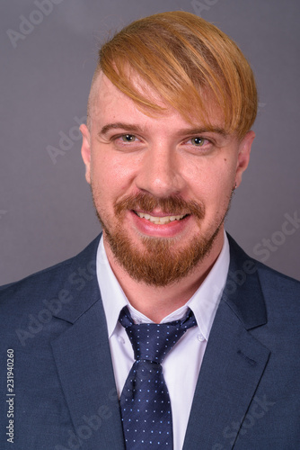 Bearded businessman with blond hair against gray background