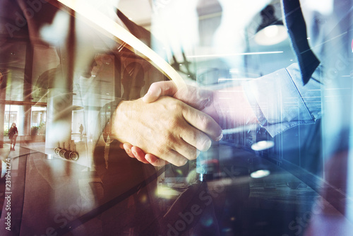 Handshaking business person in the office. concept of teamwork and partnership. double exposure