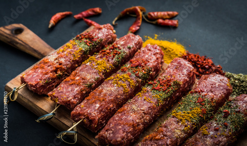 Raw kebab with spices on a black table