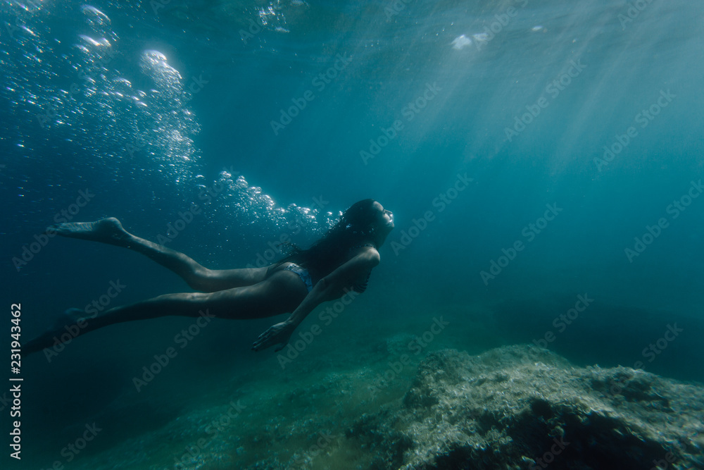 Wide shot of a woman swimming underwater Wide shot of a woman swimming underwater