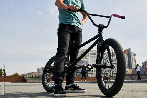 Low section portrait of unrecognizable young man standing by bmx bike in extreme sports park, copy space