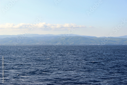 Sea landscape seascape deep blue calm sea ocean clouds sky land island mountain hill on horizon 