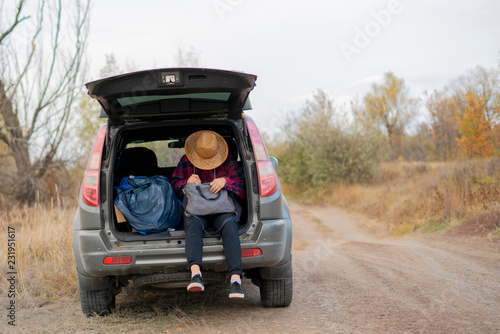 young man in summer hat searching in luggage in the car trunk in road journey f © Mihail