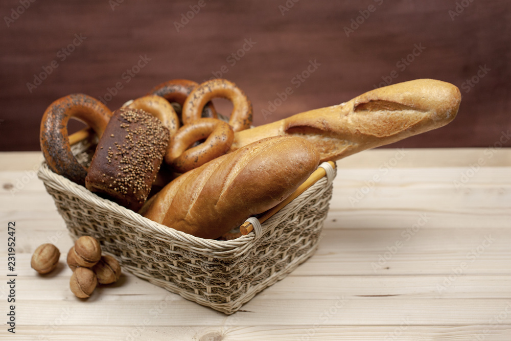 Rye bread baton and bagels in a wicker basket on a wooden table