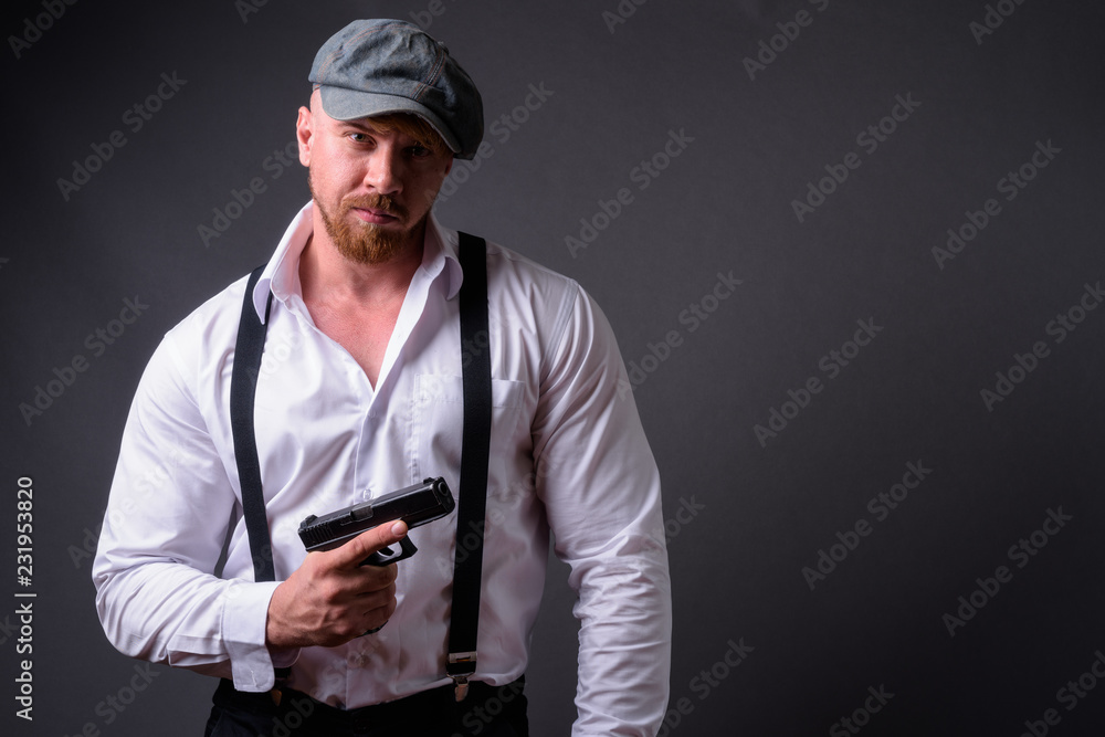 Bearded man with handgun against gray background Bearded man with handgun against gray background