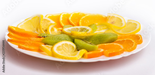 White plate with tangerines, oranges and kiwi on a festive table_