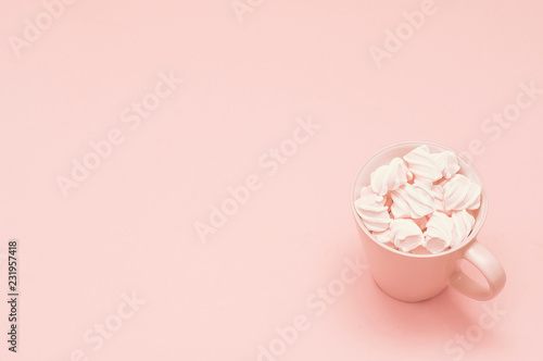 Cup and meringue on a pink background. Soft pastel color lighting. Powder color