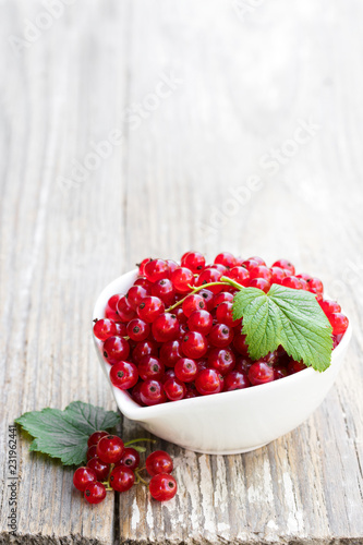 Fresh red currant in ceramic bowl on wooden table