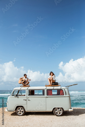 hipster boy playing guitar with girlfriend on top of retro style
