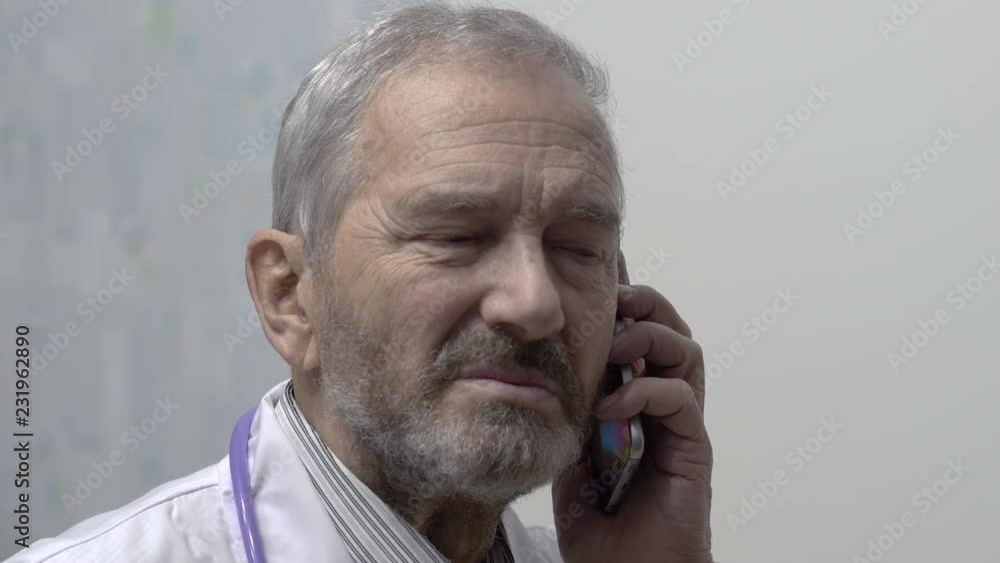 Elderly Doctor Talking On Phone In Hospital Elderly Doctor Talking On Phone In Hospital