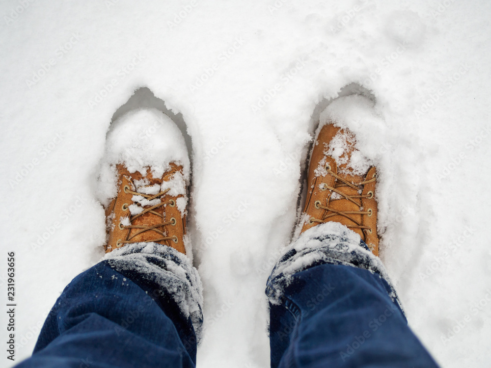Man standing in yellow boots in snow Man standing in yellow boots in snow