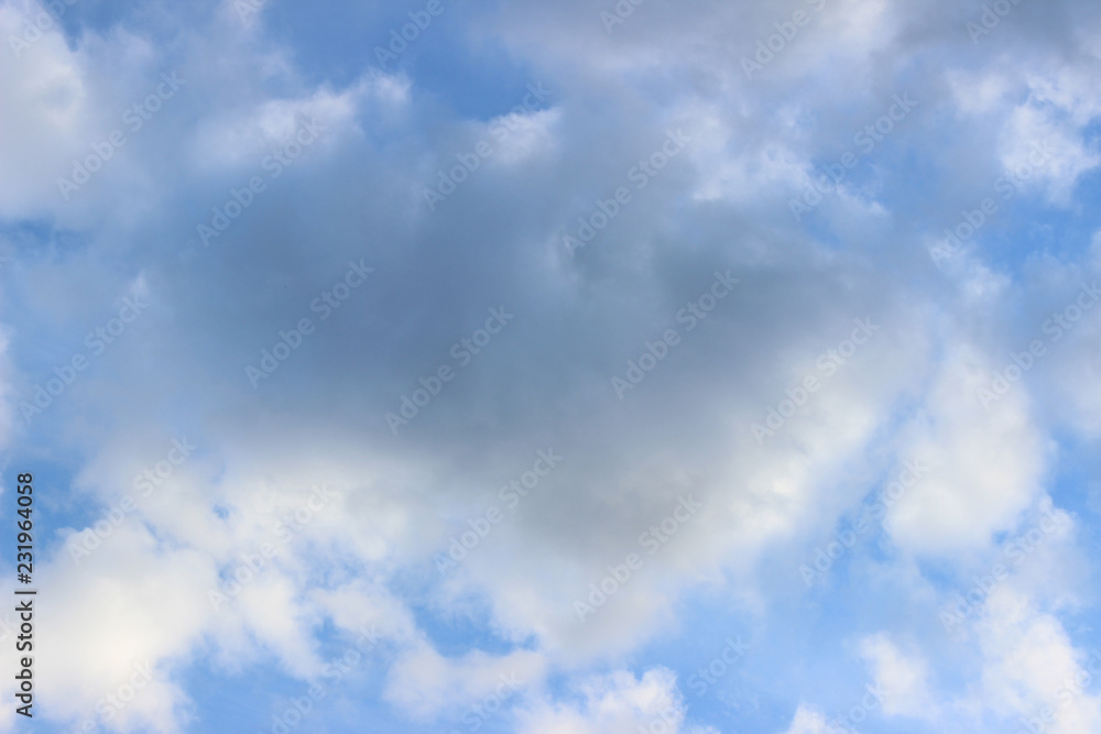 Grey cloud surrounded by white clouds on blue sky central