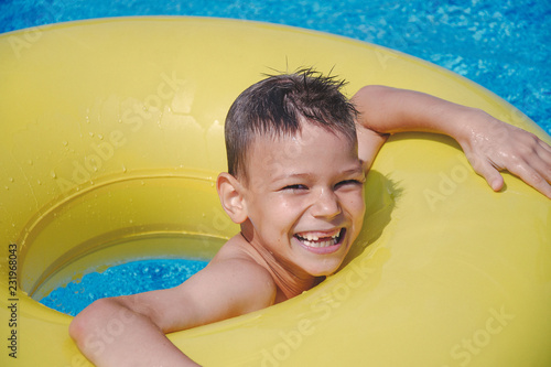 Cheerful boy enjoys floating on inflatable ring in swimming pool
