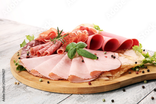 Food tray with delicious salami  pieces of sliced ham  sausage and salad. Meat platter with selection.