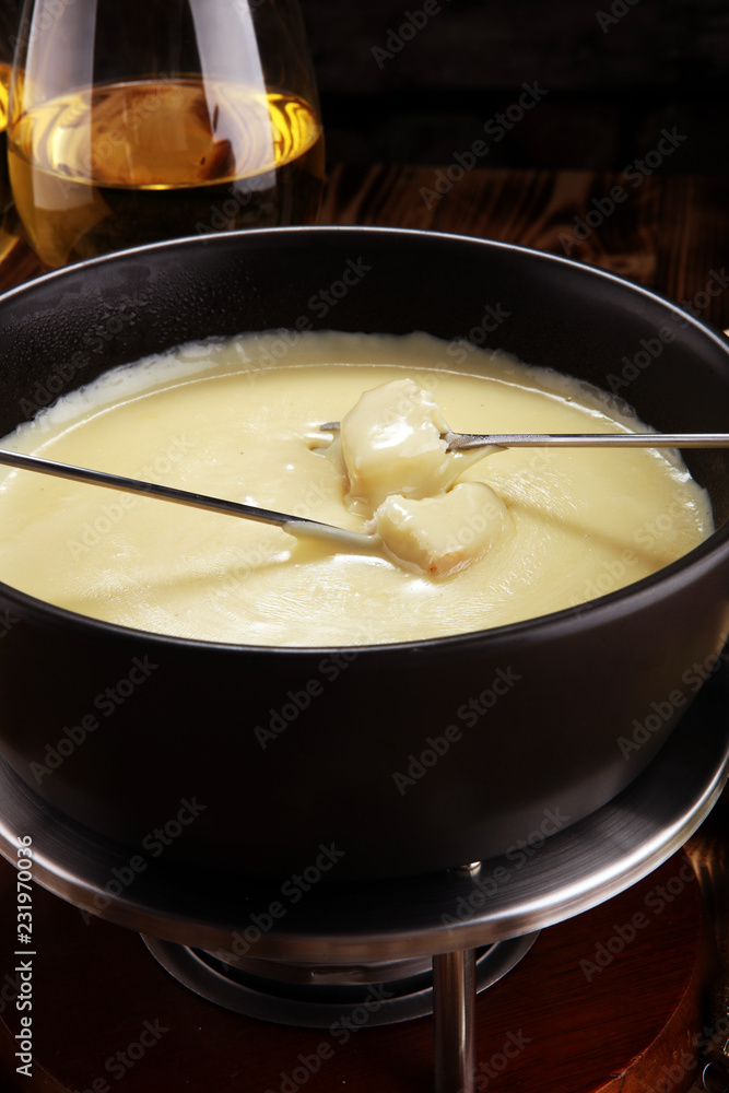 Gourmet Swiss fondue dinner on a winter evening with assorted cheese Gourmet Swiss fondue dinner on a winter evening with assorted cheese
