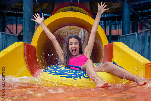 Girl in aqua park have fun riding on water slide with inflatable ring