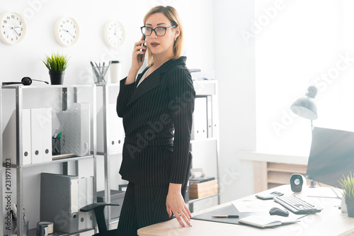 A young girl standing in the office and talking on the phone. photo