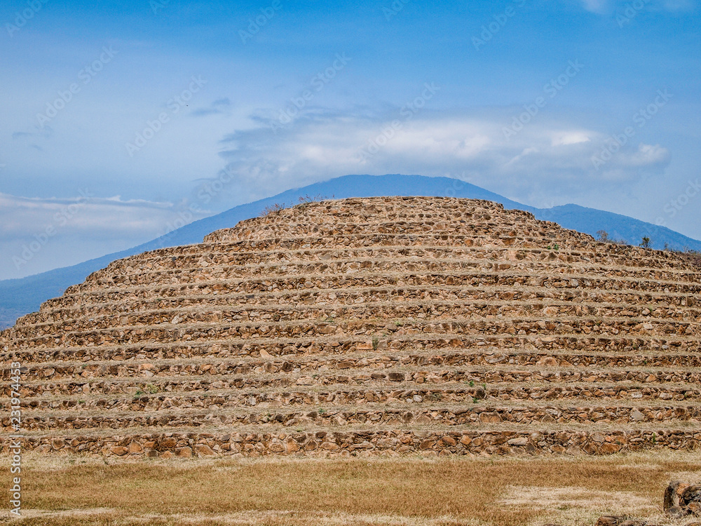 Circular pyramid against a blue sky in Guachimontones, stepped conical structures, mountain in background, used in ceremonies in honor of Ehécatl, god of the wind, day in Teuchitlán, Jalisco Mexico