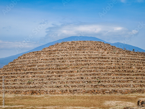 Circular pyramid against a blue sky in Guachimontones  stepped conical structures  mountain in background  used in ceremonies in honor of Eh  catl  god of the wind  day in Teuchitl  n  Jalisco Mexico