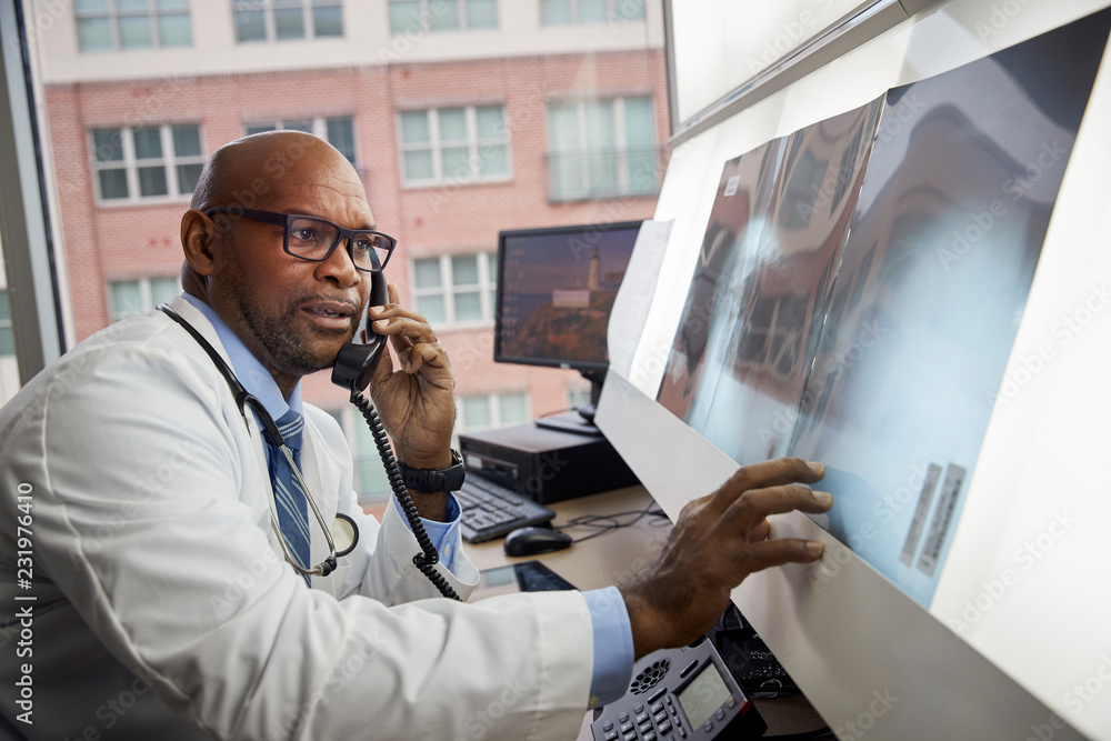 © Gregory Miller - Doctor examining x ray while talking on the phone © Gregory Miller - Doctor examining x ray while talking on the phone