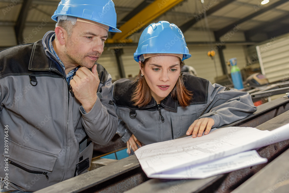 Serious workers are checking a plan in a factory Serious workers are checking a plan in a factory
