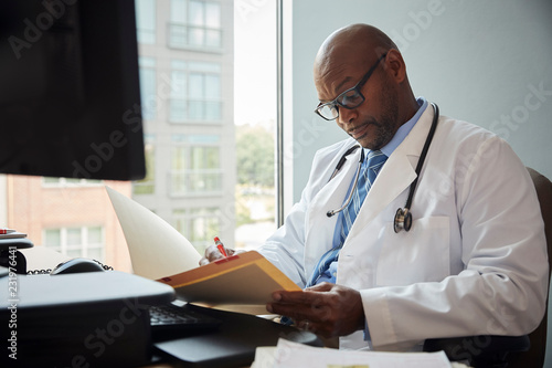 Doctor writing on file