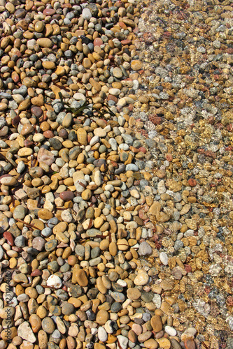 Pebbles texture with on half covered by sea water