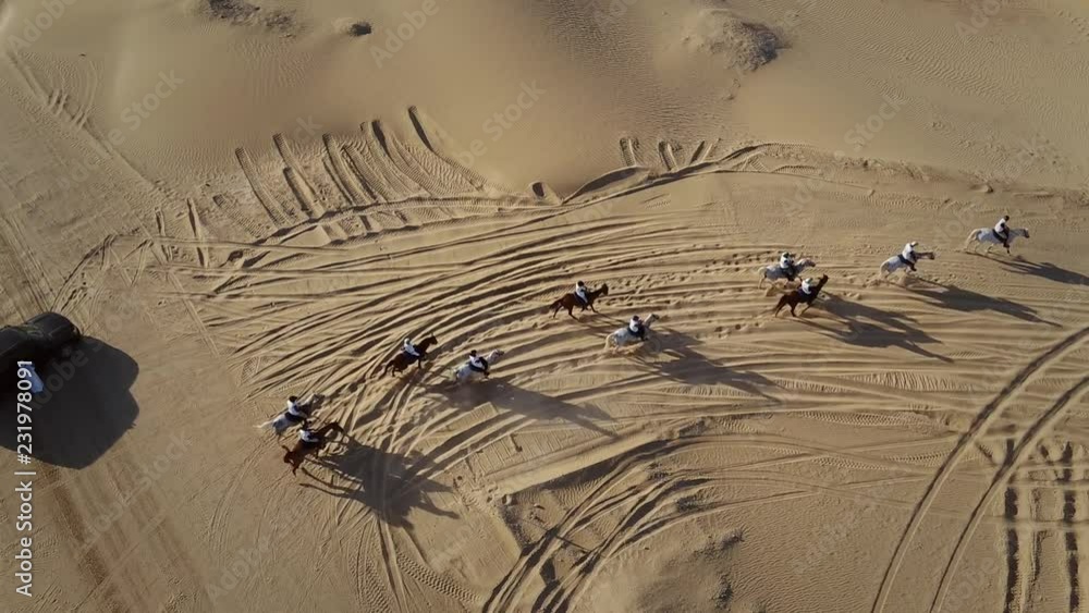 Aerial view group people riding horses on a race in the desert of Al Khatim in Abu Dhabi, U.A.E.