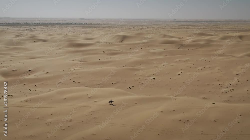 Aerial view of one person riding horse in the desert of Al Khatim in Abu Dhabi. U.A.E. Aerial view of one person riding horse in the desert of Al Khatim in Abu Dhabi. U.A.E.