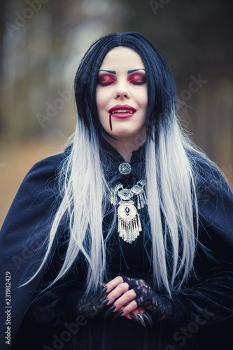 Photo of gothic vampire girl with eyes closed with blood at mouth
