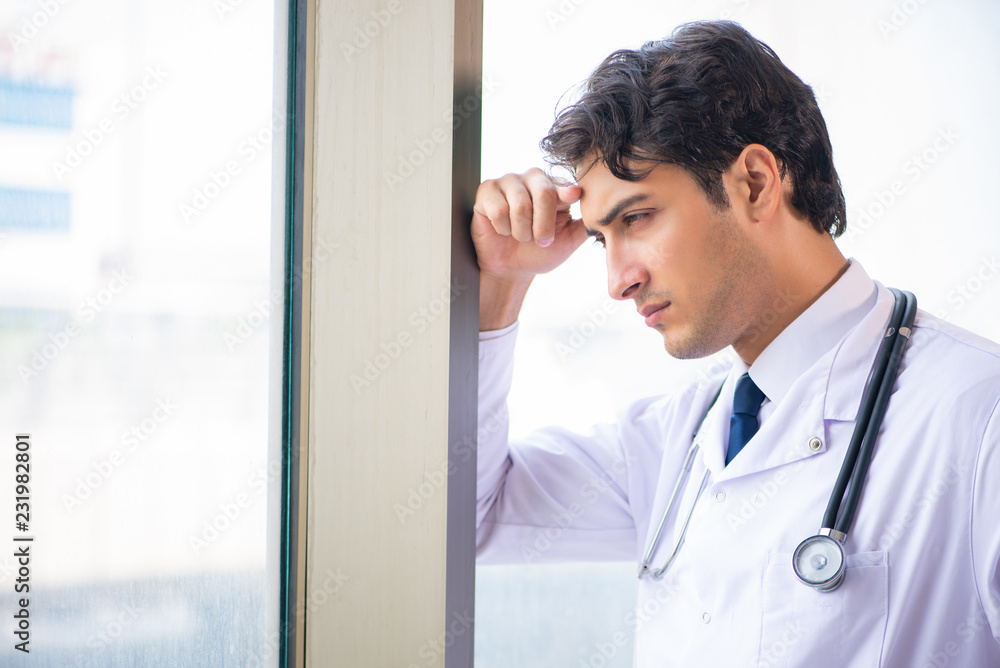 Fototapeta premium Young handsome doctor standing at the window 