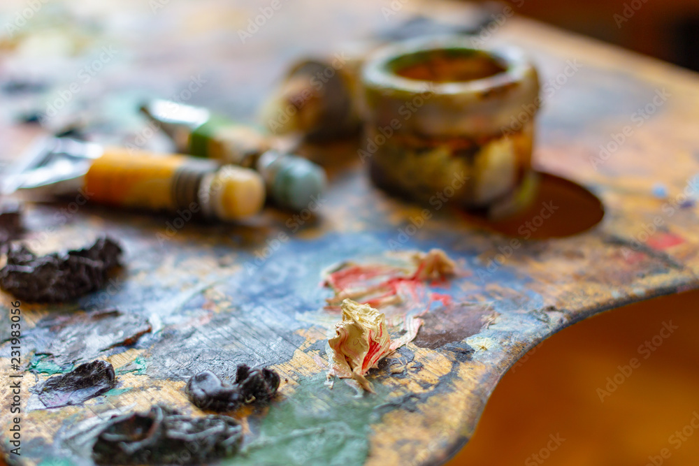 Artists' wooden palette with paints, pipes and a container for solvents with a shallow depth of field