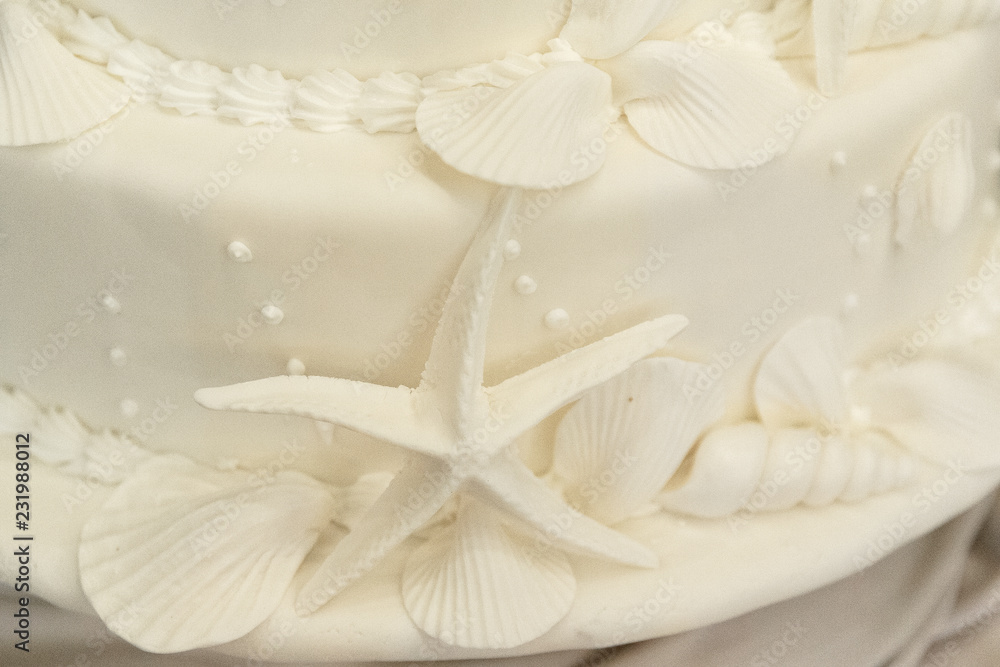 Wedding cake decorated with shells and starfish and the bride's bouquet.