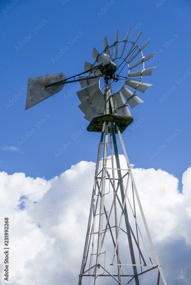 Tall metal weathervane against a cloudy blue sky Tall metal weathervane against a cloudy blue sky