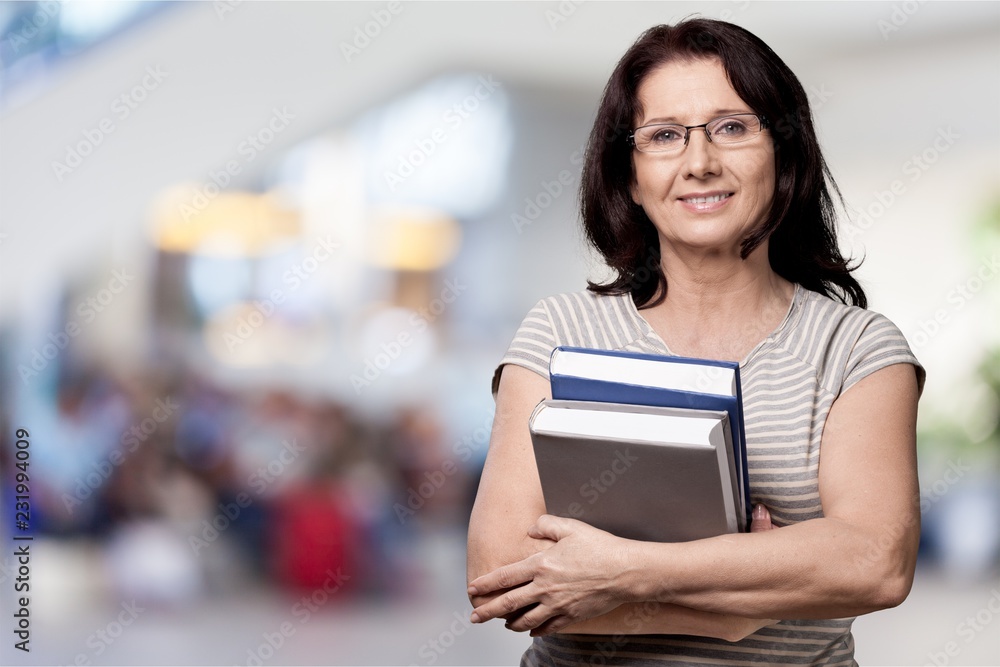 Mature woman teacher with books on background Mature woman teacher with books on background