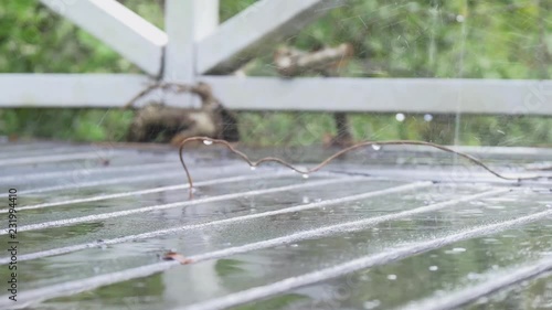 A low camera shot of a wooden terrace deck outside a house during a heavy rain as raindrops are hitting the deck and splashing everywhere. Cold and windy weather in New Zealand. photo