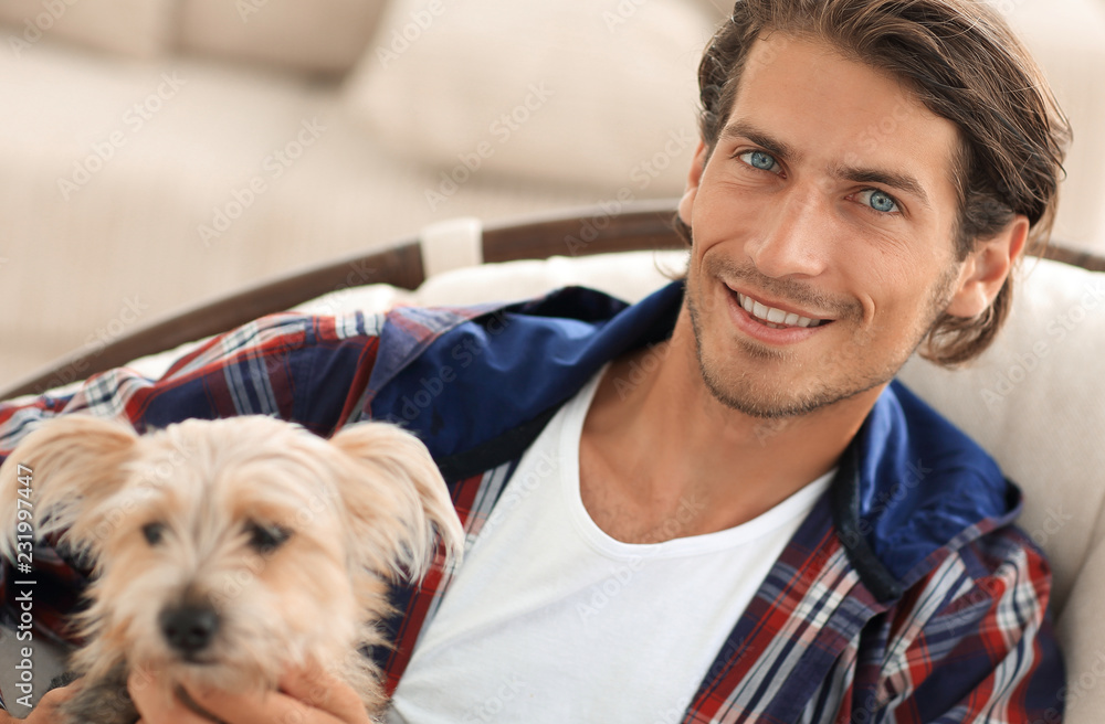 handsome guy stroking his dog while sitting in a large armchair. handsome guy stroking his dog while sitting in a large armchair.