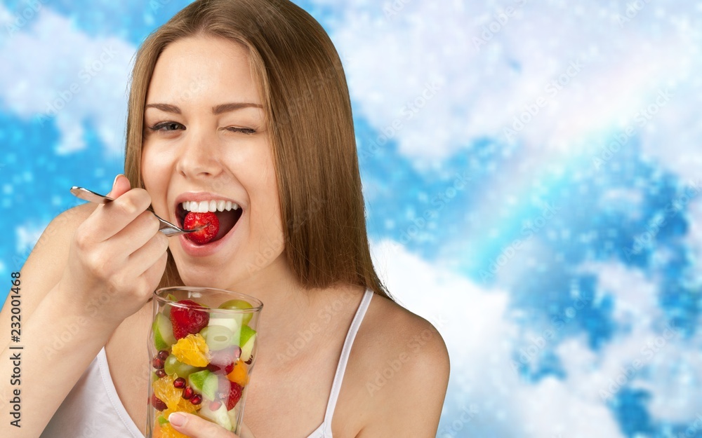 Young woman eating fruits from glass on blurred background Young woman eating fruits from glass on blurred background