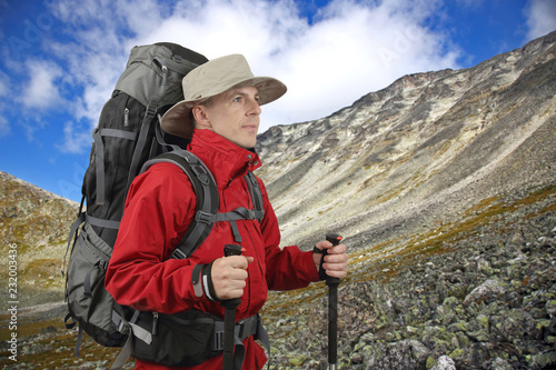 equipped with traveler in a red jacket with Hiking poles looks into the distance