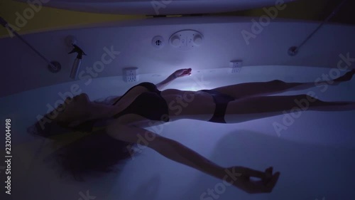 Young Woman in float tank, sensory depravation tank at spa