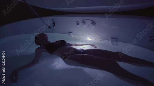 Young Woman in float tank, sensory depravation tank at spa