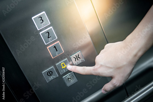 Male forefinger pressing on emergency stop and alarm button in elevator (lift). Mechanical engineering concept photo