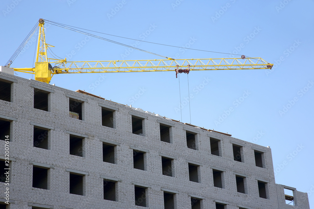 Construction crane on the construction of a brick house