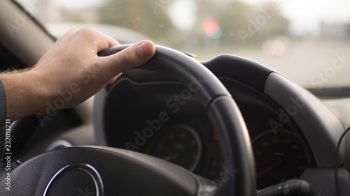 Male hand on steering wheel inside car
