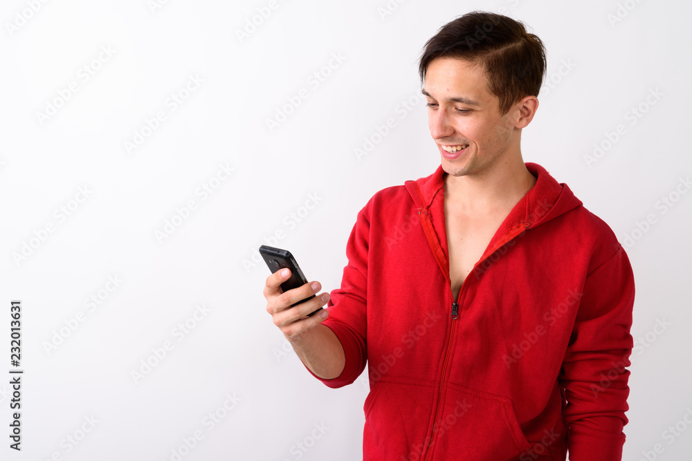 Studio shot of happy young handsome man smiling while using mobi Studio shot of happy young handsome man smiling while using mobi