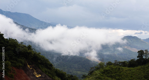 View of the mountains with fog above green hills.