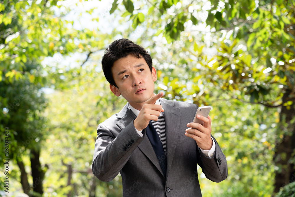 外で携帯電話を確認するビジネスマン